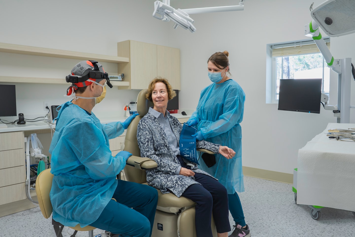 Doctor and nurse check on smiling patient in examination room.